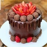 Bolo de chocolate coberto com morangos e brigadeiros