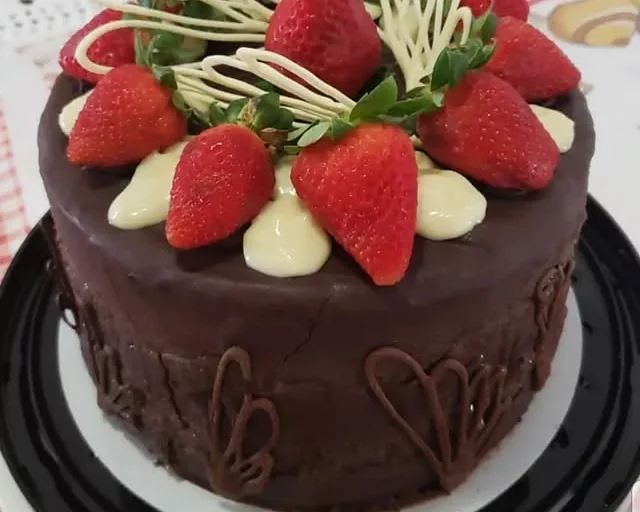 Torta coberta de chocolate e decorada com morangos inteiros