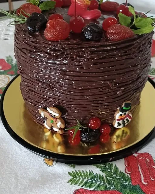 Torta de chocolate decorada com morangos, cerejas e biscoitos natalinos
