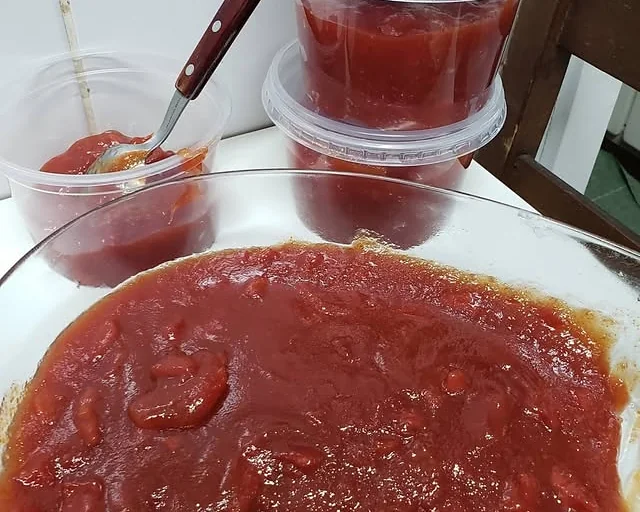 Doce de compota vermelho em potes e numa travessa
